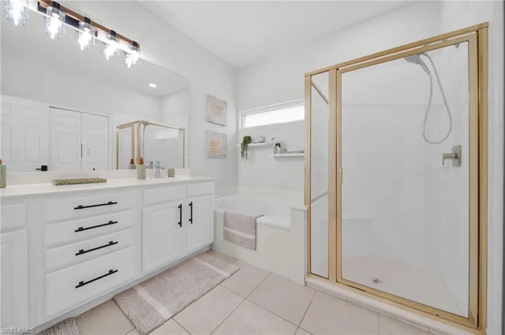 Full bathroom with a shower stall, a garden tub, vanity, and light tile patterned flooring