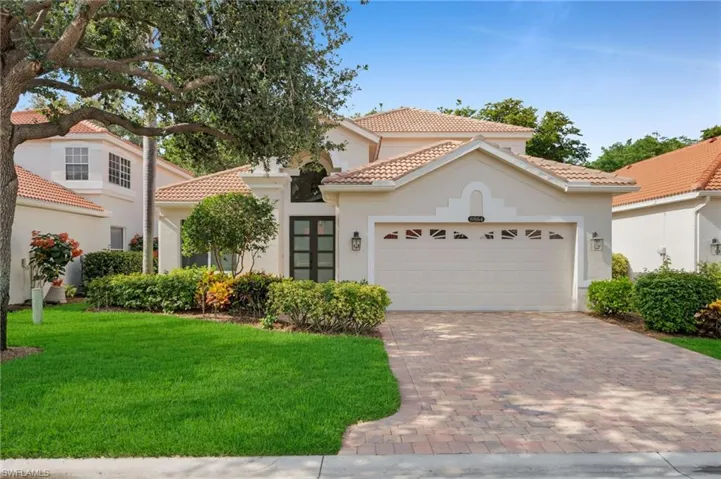 Mediterranean / spanish-style home with a tiled roof, stucco siding, decorative driveway, and a front yard