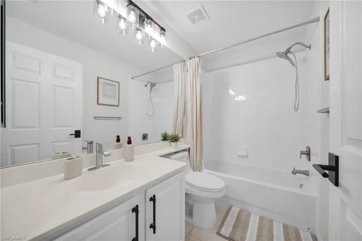 Full bath featuring vanity, shower / bath combination with curtain, and light tile patterned floors