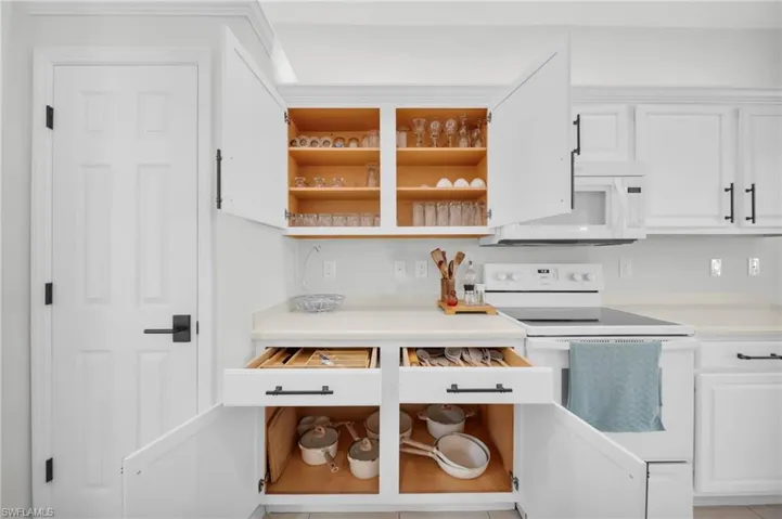 Kitchen featuring white appliances, open shelves, white cabinets, and light countertops