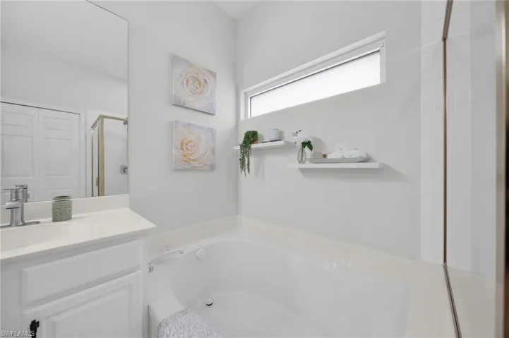Bathroom with a garden tub, a stall shower, and vanity