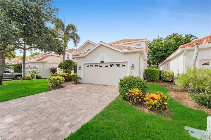 Mediterranean / spanish house with a tiled roof, decorative driveway, a front yard, stucco siding, and a garage
