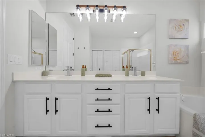 Full bath with double vanity, a bath, a shower stall, and a closet