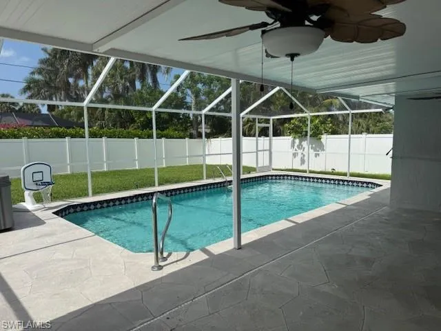 View of spacious, fenced backyard with a pool cage enclosing the lanai and a large saltwater pool.