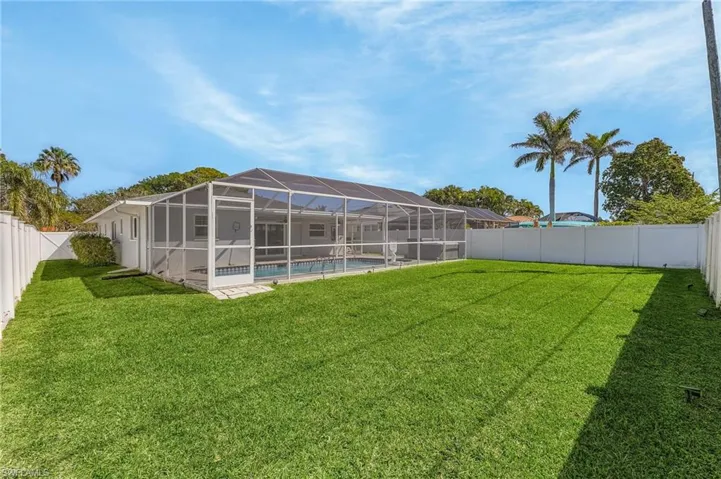View of yard featuring a pool cage with an oversized pool, an above-ground spa and a fenced backyard.