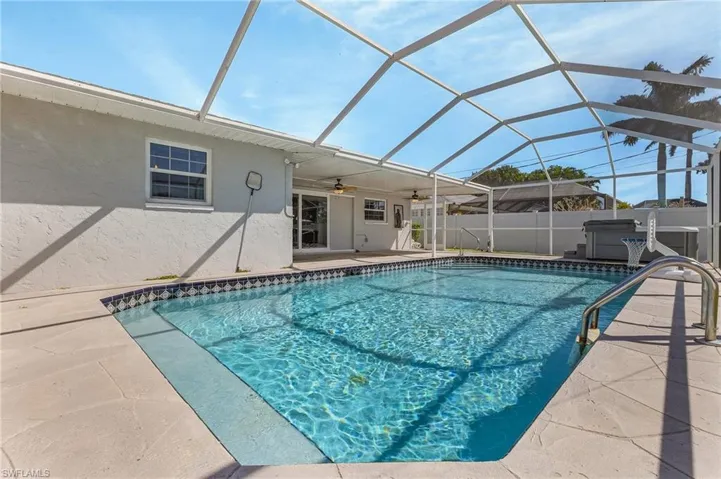 View of the spacious pool featuring with an above-ground spa and fenced lanai.