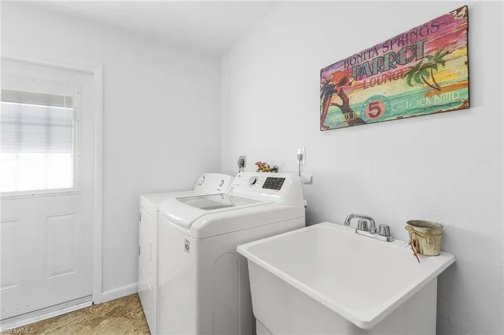 Laundry area with a sink, separate washer and dryer, and doors that access the garage and the side yard.