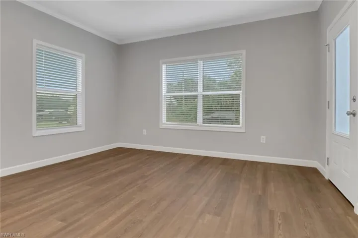 Living room with laminated flooring, crown molding, and a wealth of natural light