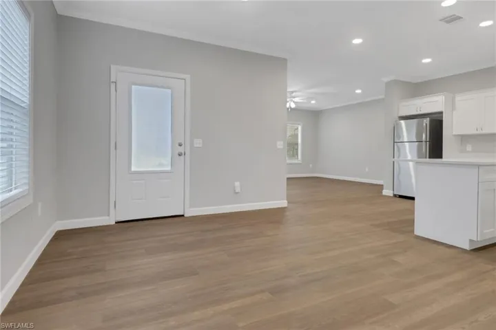 living room with laminated floors, ceiling fan, and crown molding