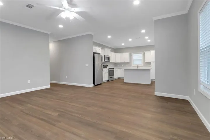 living room with laminated flooring, ceiling fan, and crown molding