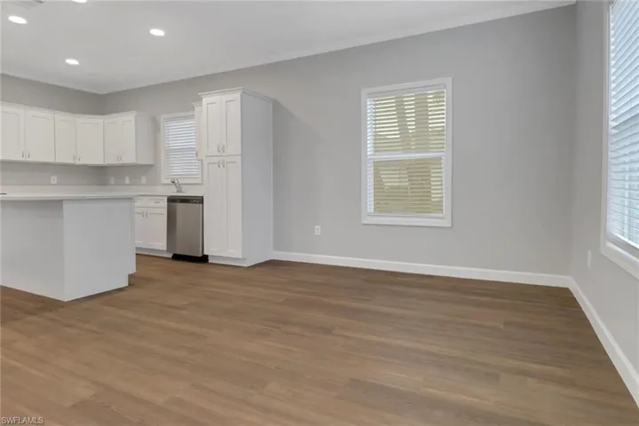 Kitchen with laminated floors, ss appliances white cabinetry, and quartz countertops