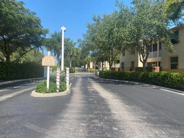 View of asphalt road with curbs, a gate, and a gated entry