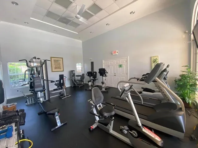 Gym with a towering ceiling, a ceiling fan, and a paneled ceiling