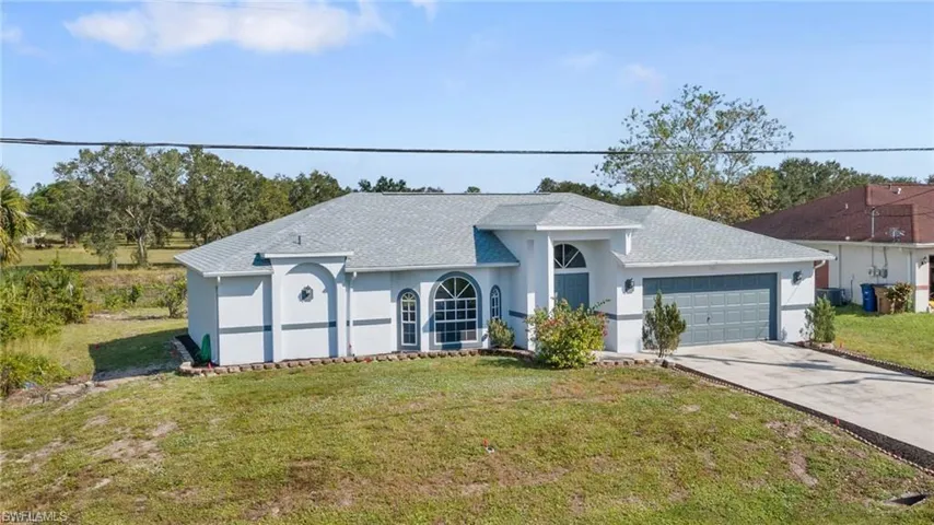 Single story home with a front lawn, stucco siding, roof with shingles, driveway, and a garage