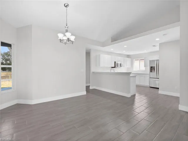 Unfurnished living room featuring suspended lighting and wood finish floors