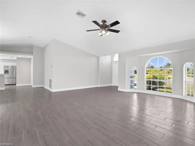 Unfurnished living room featuring a ceiling fan, lofted ceiling, and wood finish floors