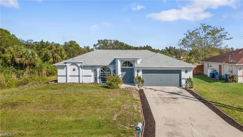 Single story home with a front yard, concrete driveway, stucco siding, a garage, and a shingled roof