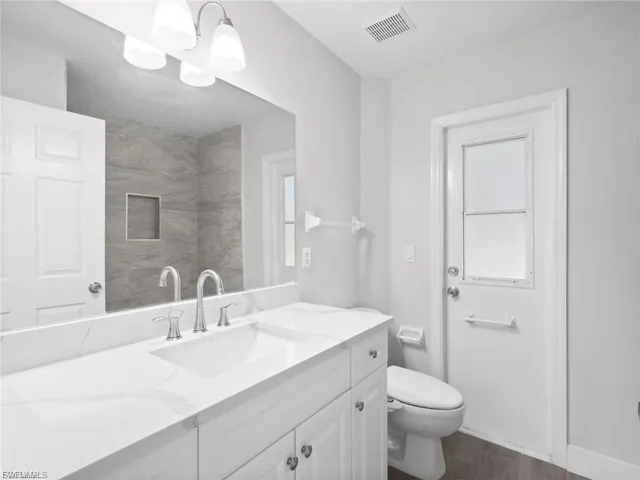 Full bath with vanity, dark wood finished floors, and hanging lights