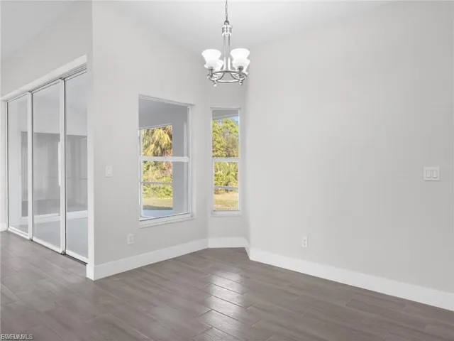 Unfurnished dining area featuring dark wood finished floors and a chandelier