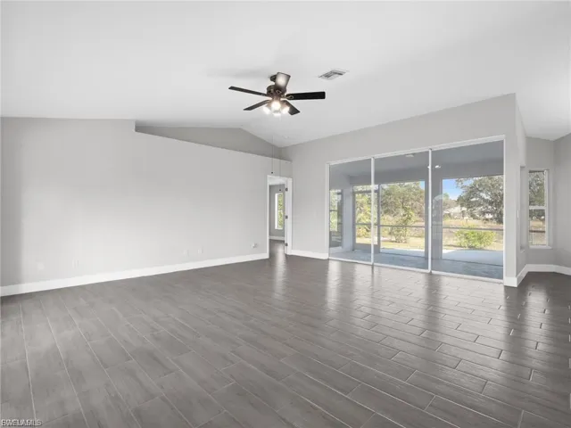 Spare room with ceiling fan, wood finish floors, and vaulted ceiling