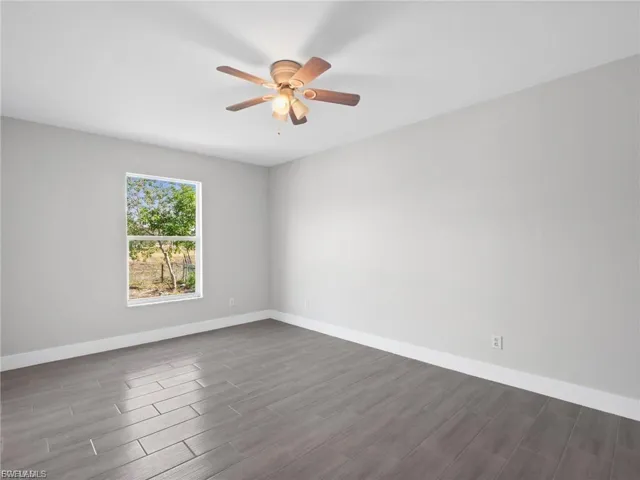 Spare room featuring dark wood-style floors and ceiling fan