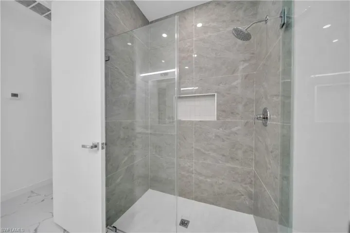 Walk-in shower with full-height tile surround, integrated niche, rain shower head, and glass enclosure