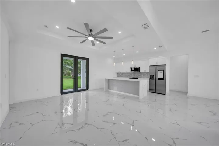 Open-concept living space featuring high-gloss marbled tile flooring, recessed lighting, and a contemporary ceiling fan