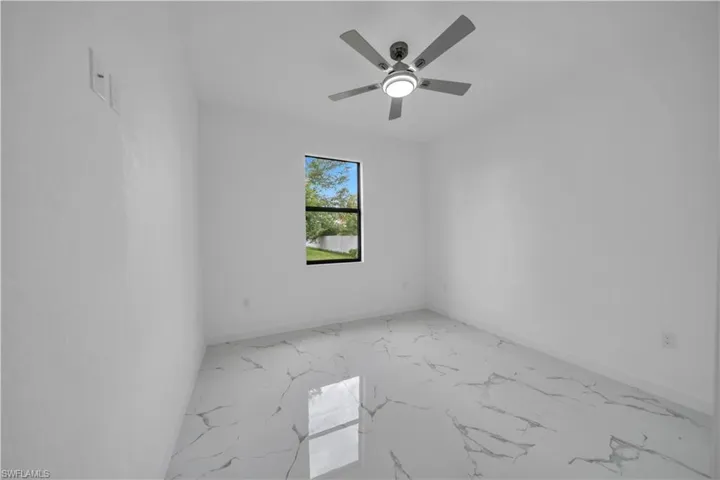 Room with white walls and polished tile flooring, featuring a window and a ceiling fan with integrated lighting