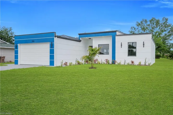 Modern exterior featuring white siding with blue accents, a flat roofline, and a well-maintained lawn