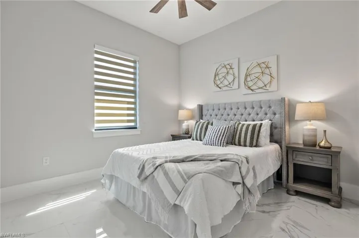 Bedroom with marble finish floor, baseboards, and a ceiling fan