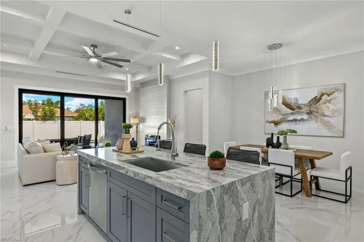 Kitchen featuring a sink, a ceiling fan, marble finish floor, light stone counters, and dishwasher