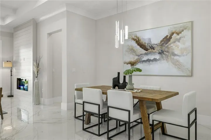 Dining space with baseboards, marble finish floor, and a glass covered fireplace