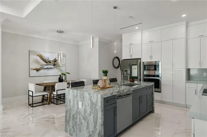 Kitchen featuring white cabinets, appliances with stainless steel finishes, light stone counters, and recessed lighting