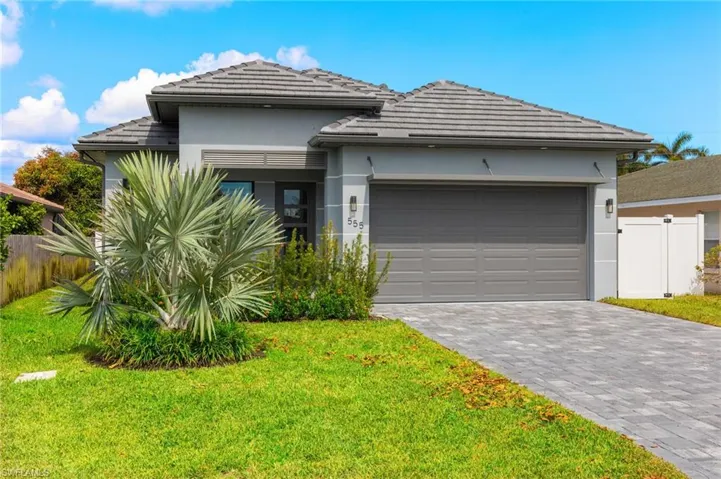Prairie-style home featuring stucco siding, a tile roof, a front yard, and fence