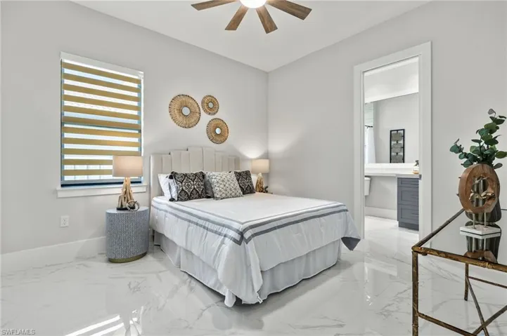 Bedroom with marble finish floor, baseboards, a ceiling fan, and ensuite bathroom