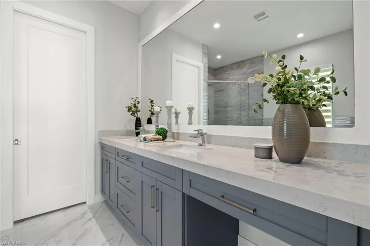 Full bathroom featuring a marble finish shower, a sink, double vanity, visible vents, and recessed lighting