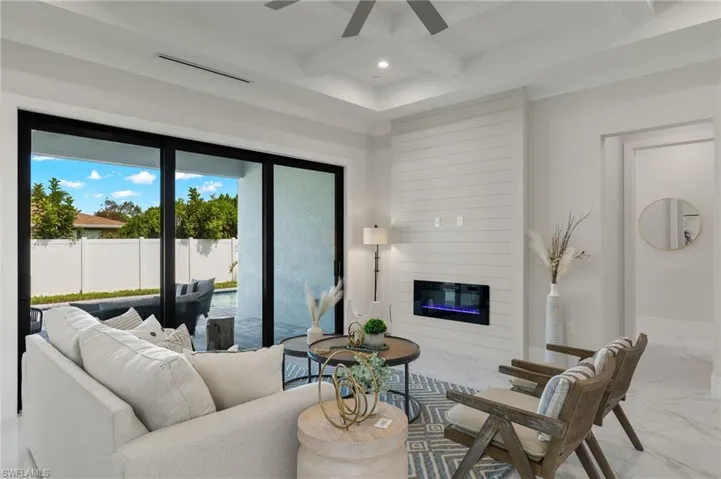 Living area featuring marble finish floor, ceiling fan, beamed ceiling, a fireplace, and visible vents
