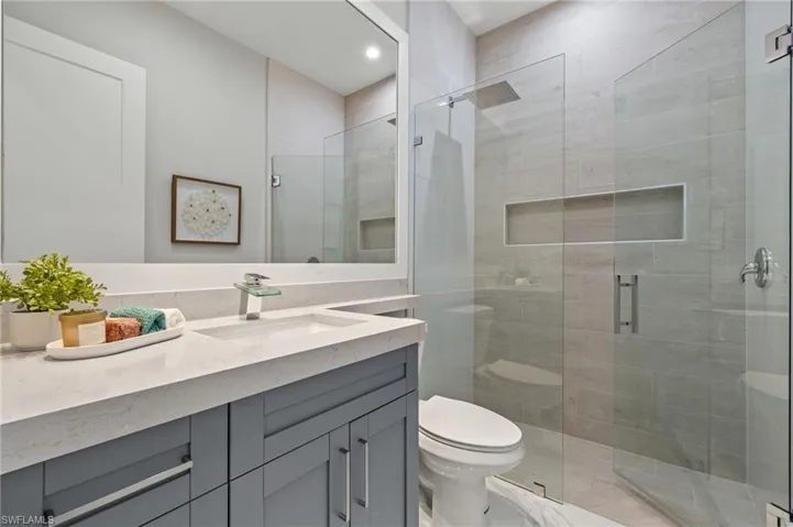 Bathroom featuring recessed lighting, a shower stall, toilet, and vanity