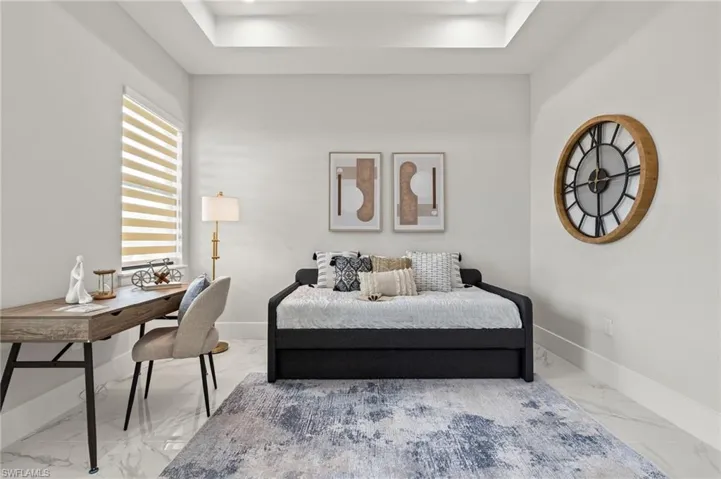 Bedroom with marble finish floor, baseboards, and a raised ceiling