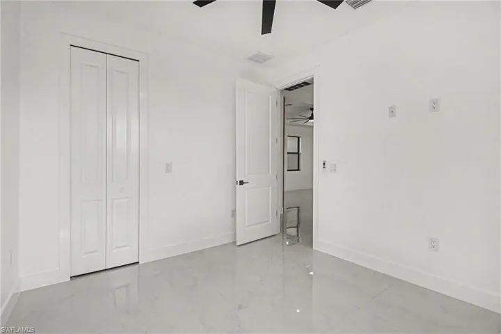 Unfurnished bedroom with a closet, a ceiling fan, and light marble finish floors