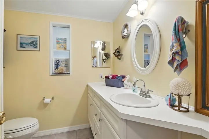 Bathroom with ornamental molding, vanity, and tile patterned flooring