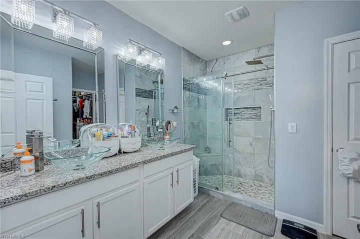 Bathroom with double vanity, a marble finish shower, and a walk in closet