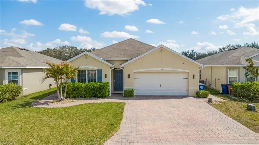 Ranch-style home featuring stucco siding, an attached garage, a front yard, decorative driveway, and roof with shingles