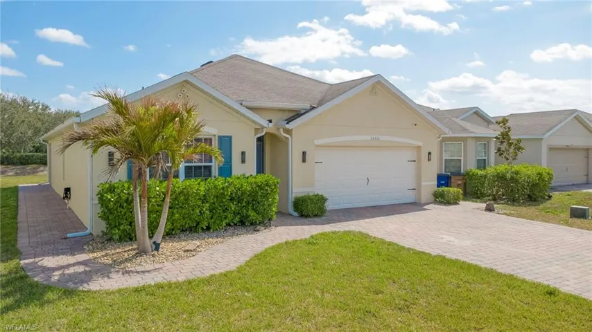 Ranch-style house featuring an attached garage, stucco siding, driveway, and a front yard