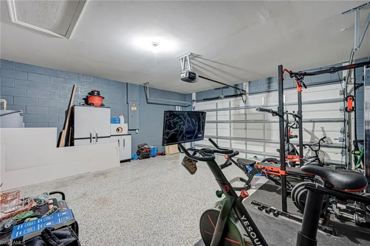 Workout room with a garage, electric panel, and concrete block wall