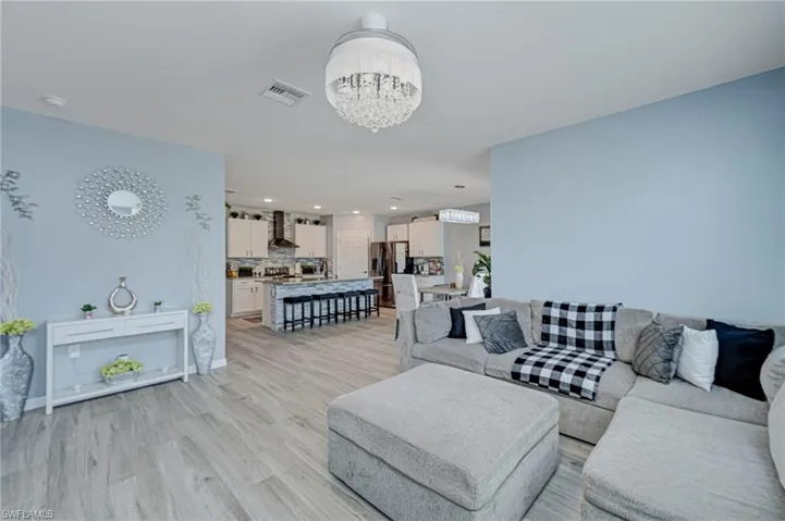 Living area with light wood-type flooring and suspended lighting
