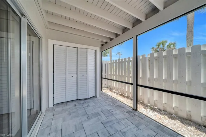 Screened patio featuring paver flooring, louvered bi-fold doors, and a slatted privacy fence