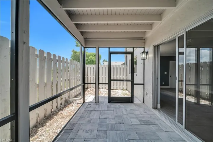 Screened patio featuring paver flooring, exposed beam ceiling, exterior wall lantern, and sliding glass door access to the interior