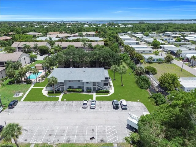 Multi-unit dwelling featuring a central courtyard with established landscaping, a community pool, and ample surface parking