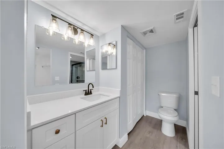 Bathroom featuring a single vanity with a white countertop and undermount sink, a bronze-finish faucet, and coordinating cabinet hardware